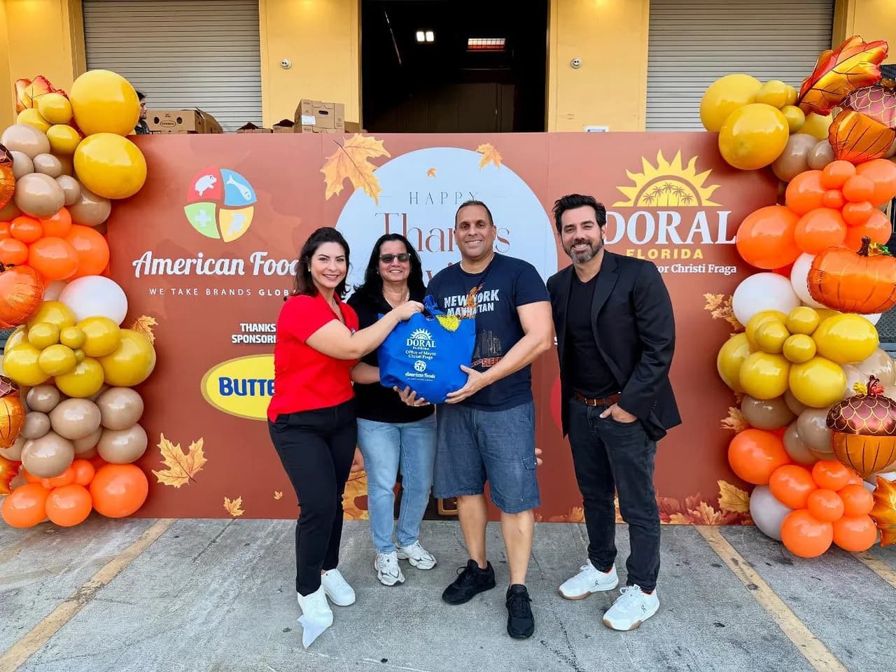 The American Foods team handing out Thanksgiving food bags with the City of Doral, in front of our sponsor backdrop
