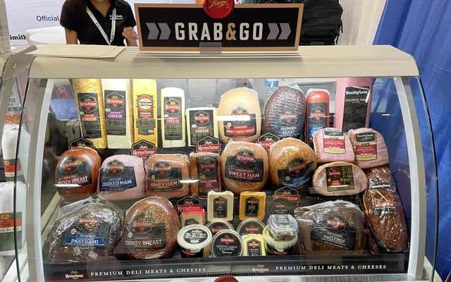 Vitrina de deli Kretschmar con carnes frías y quesos bajo un letrero "Grab & Go"